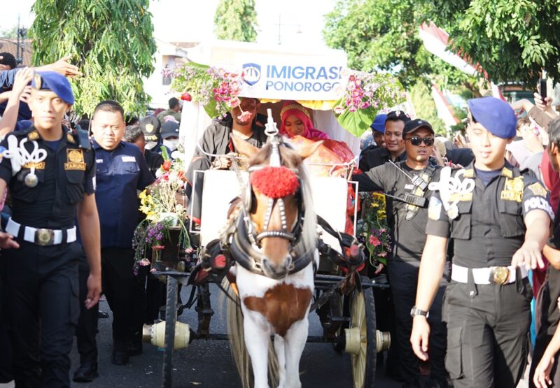Kepala Kantor Imigrasi Ponorogo, Happy Dipayuda, bersama Ketua Dharma Wanita Persatuan (DWP) Kantor Imigrasi Ponorogo, Dini Happy Dipayuda, nai kereta kuda dalam rangkaian Grebeg Suro 2025 melalui keikutsertaan dalam Kirab Pusaka, Pawai Lintas Budaya, dan Jamasan Pusaka yang digelar pada Kamis (26/6/2025).(Foto:Humas Kanim Ponorogo)