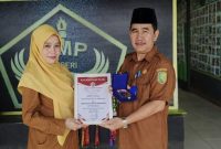 Kepala SMPN 2 Sambas, Urai Sumadi, S.Pd., (kanan) memperlihatkan Penghargaan dari MURI.(Foto:Dok.Pribadi)