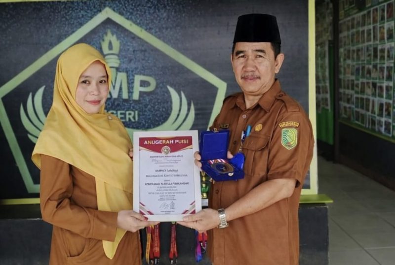 Kepala SMPN 2 Sambas, Urai Sumadi, S.Pd., (kanan) memperlihatkan Penghargaan dari MURI.(Foto:Dok.Pribadi)